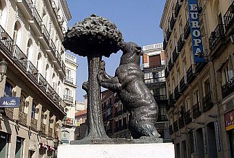 Posąg brązowego niedźwiedzia, zjadającego owoce z drzewa poziomkowego 